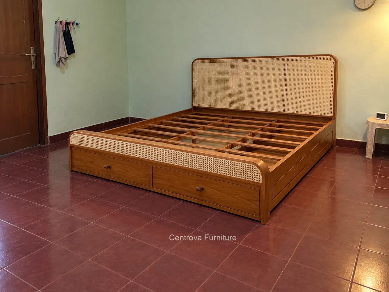 Dipan kayu dengan panel rotan dan dua laci ujung dalam kamar sederhana.