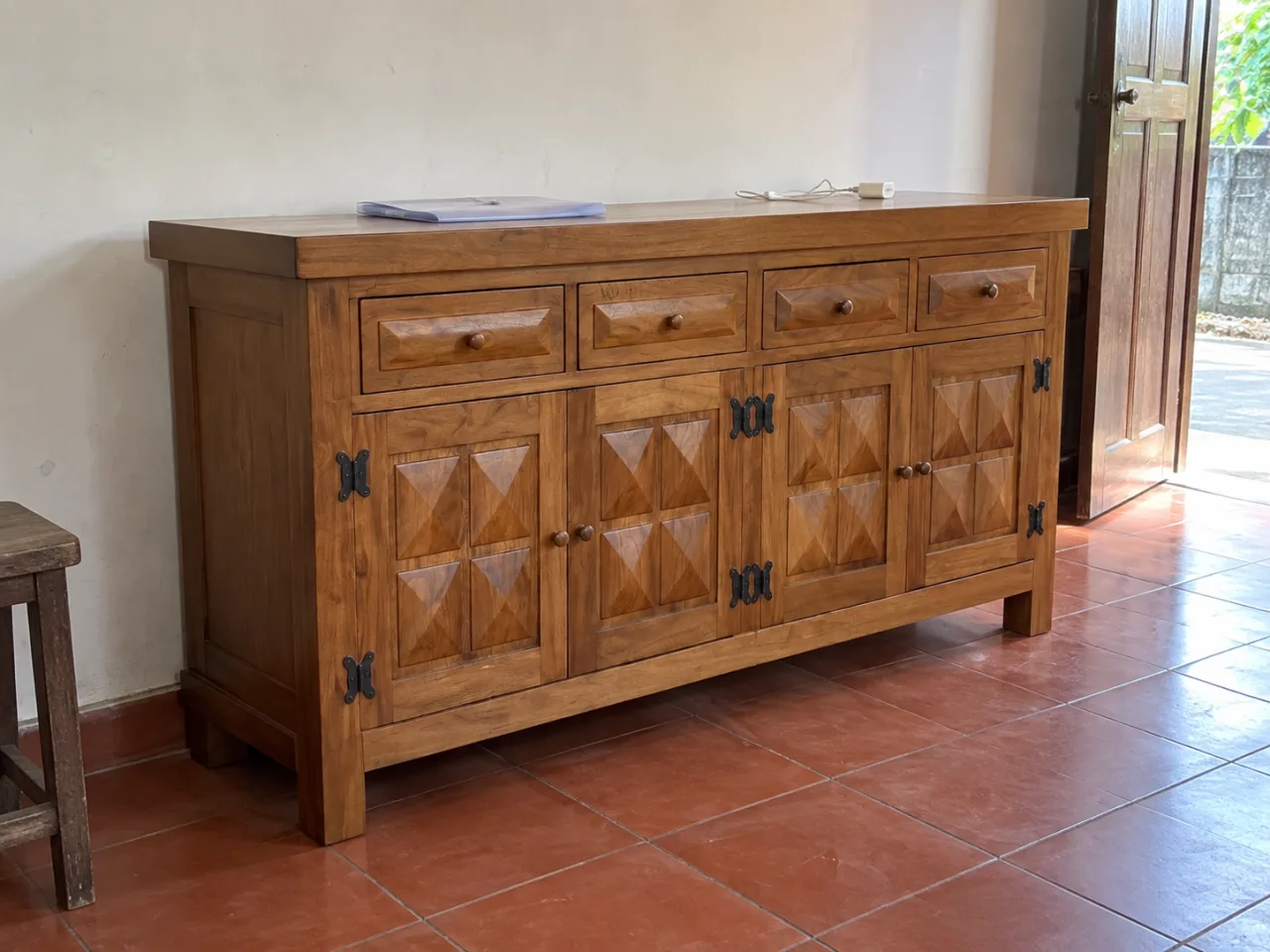 Penataan bufet kayu berdetail piramida di ruang keluarga dengan lantai merah bata.