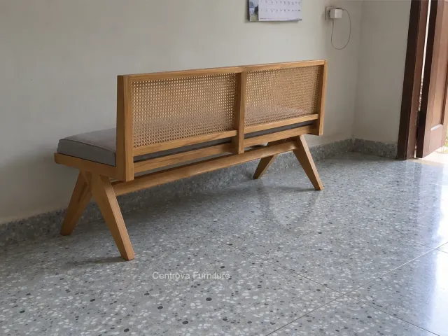 Wooden bench with a cane backrest in a simple family room corner.