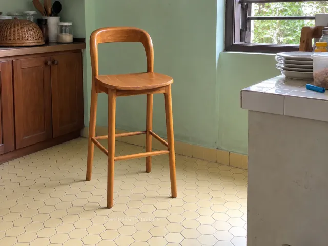 Wooden bar chair with an open back in a simple home kitchen corner.